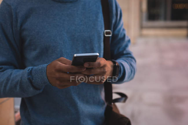 Бизнесмен пользуется мобильным телефоном на улице в солнечный день — стоковое фото