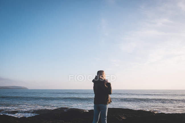 Vista trasera de la mujer de pie en una playa - foto de stock