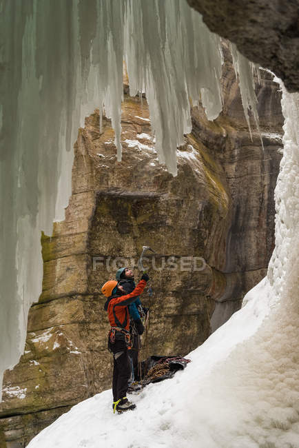 Пара стоящих рядом с скалистой горой зимой — стоковое фото