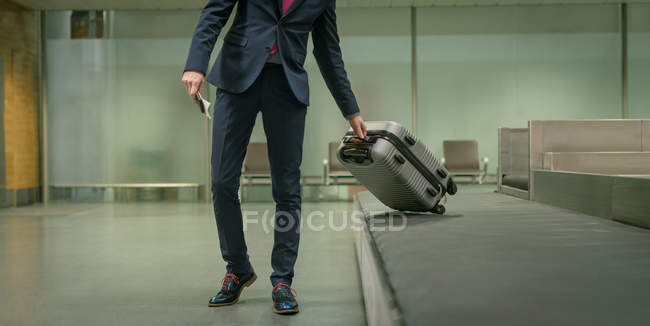 Бизнесмен забирает багаж из багажной карусели в аэропорту — стоковое фото