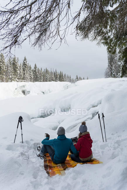Couple sitting together on a snowy landscape during winter — Stock Photo