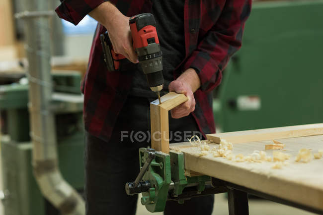 Sección media del carpintero masculino utilizando la máquina de perforación en el taller - foto de stock