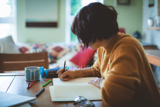Жінка малює ескіз у книзі вдома — стокове фото