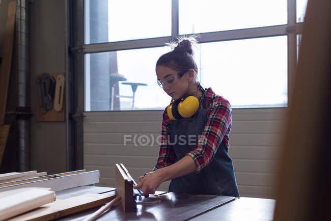 Young female carpenter working in workshop — Stock Photo