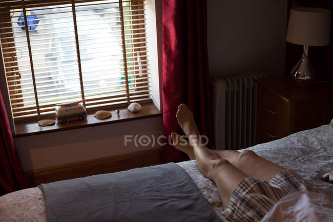 Frau entspannt sich mit am Knöchel gekreuzten Beinen im Schlafzimmer zu Hause — Stockfoto