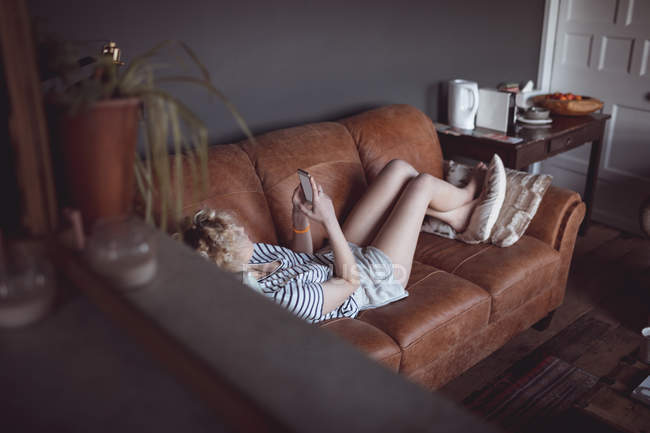 Жінка використовує мобільний телефон у вітальні вдома — стокове фото