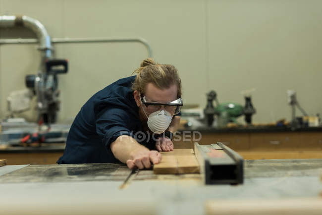 Carpinteiro macho fazendo medições de madeira na oficina — Fotografia de Stock