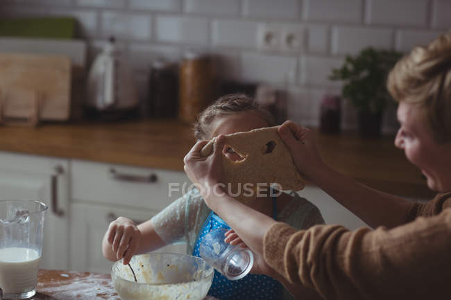 Madre e hija preparando magdalena en la cocina en casa - foto de stock