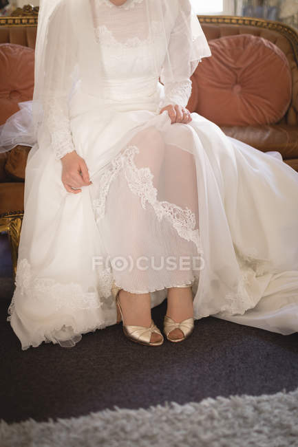 Partial view of Bride in wedding dress relaxing on sofa — Stock Photo