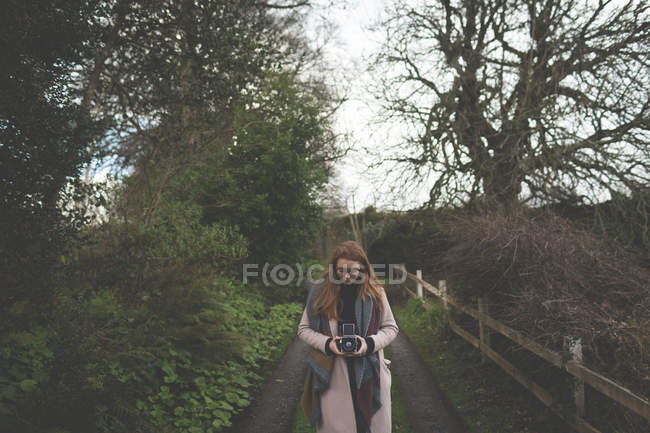 Donna che scatta foto con fotocamera vintage in campagna — Foto stock
