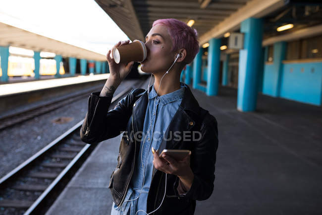 Mulher elegante tendo café enquanto espera na estação ferroviária — Fotografia de Stock