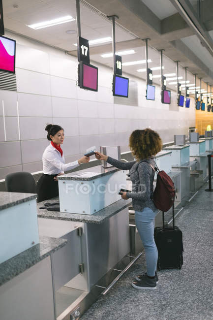 Assistente de check-in da companhia aérea entrega passaporte para pendulares no balcão no terminal do aeroporto — Fotografia de Stock