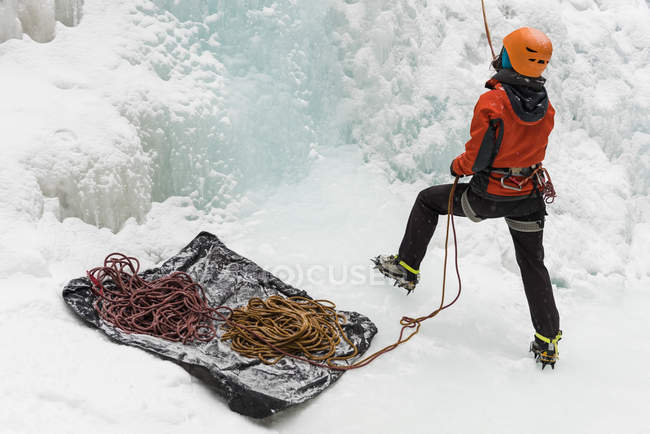 Vista trasera de la escaladora femenina sosteniendo una cuerda durante el invierno - foto de stock