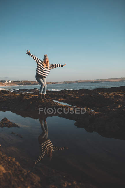 Frau steht an einem sonnigen Tag mit ausgestreckten Armen am Strand — Stockfoto