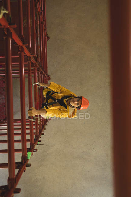 Jovem trabalhador do sexo masculino escalando andaimes na estação solar — Fotografia de Stock