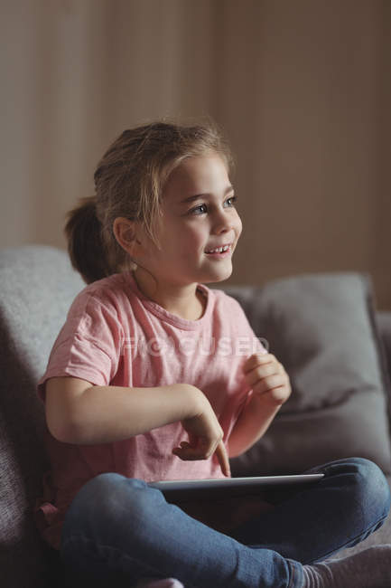 Маленька дівчинка використовує цифровий планшет у вітальні вдома — стокове фото
