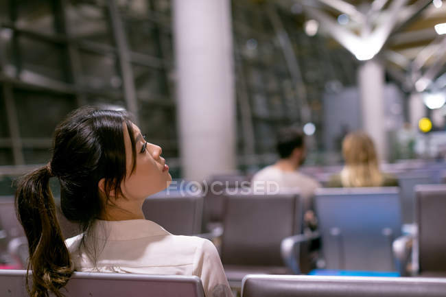 Mujer pensativa esperando en la sala de espera en el aeropuerto - foto de stock