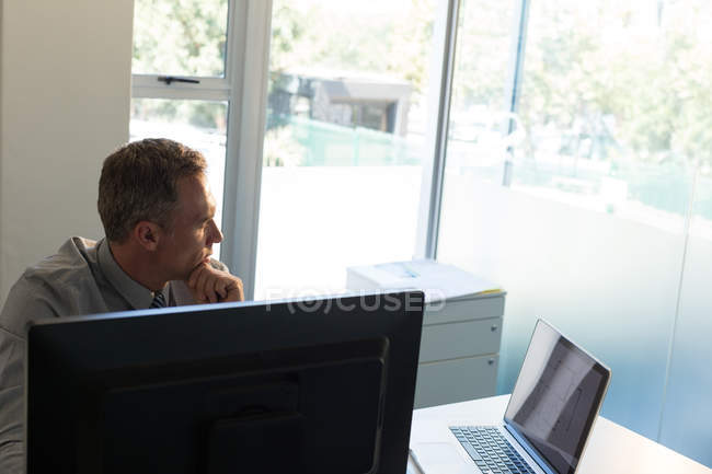 Задумчивый бизнесмен сидит за столом в офисе — стоковое фото