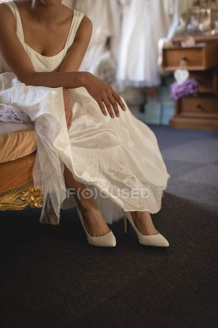 Imagen recortada de novia en vestido de novia relajante en el sofá - foto de stock