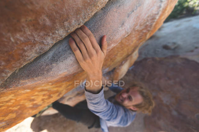 Randonneur masculin escalade montagne rocheuse à la campagne par une journée ensoleillée — Photo de stock