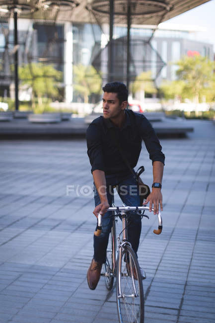 Young businessman riding a bicycle in office premises — Stock Photo