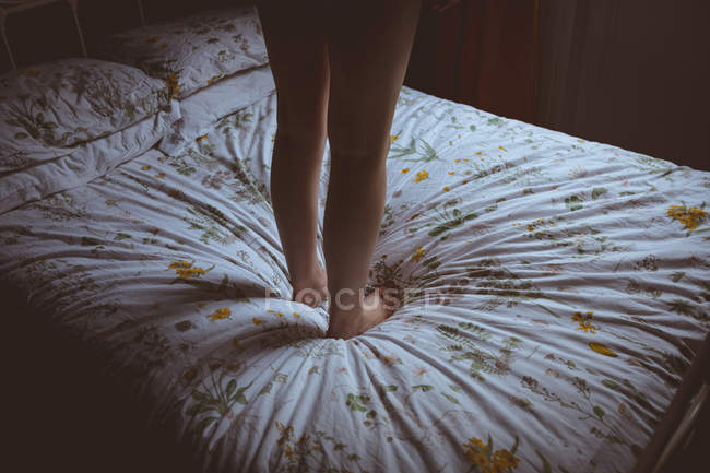 Жінка стоїть на ліжку в спальні вдома — стокове фото