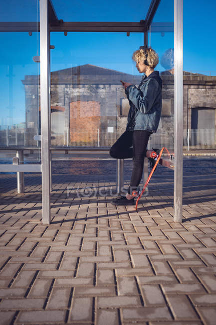 Frau benutzt an sonnigem Tag Handy an Bushaltestelle — Stockfoto