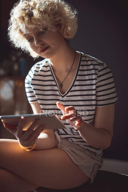 Женщина, использующая цифровой планшет в гостиной дома — стоковое фото