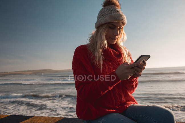 Mujer joven usando teléfono móvil en la playa - foto de stock