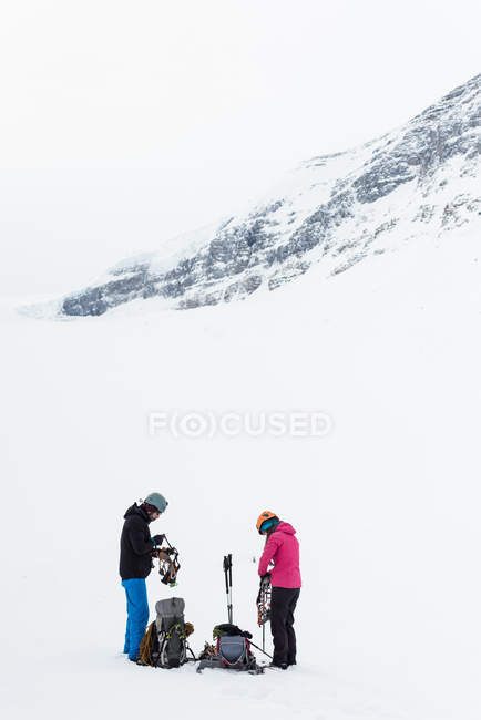 Пара носить ремни безопасности на заснеженной горе в течение зимы — стоковое фото