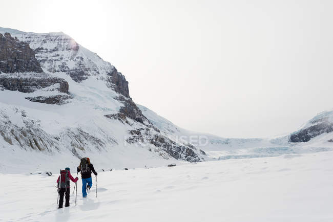 Casal andando em uma montanha coberta de neve durante o inverno — Fotografia de Stock
