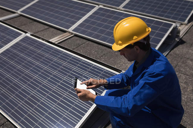 Рабочий мужчина, использующий цифровой планшет на солнечной станции в солнечный день — стоковое фото