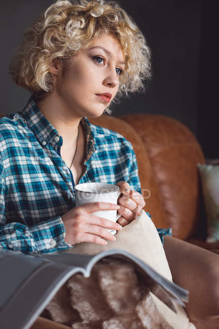 Продуманий одна жінка кави у вітальні на дому — стокове фото