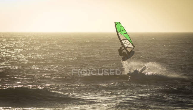 Surfeur masculin surfant avec planche de surf et cerf-volant à la plage — Photo de stock