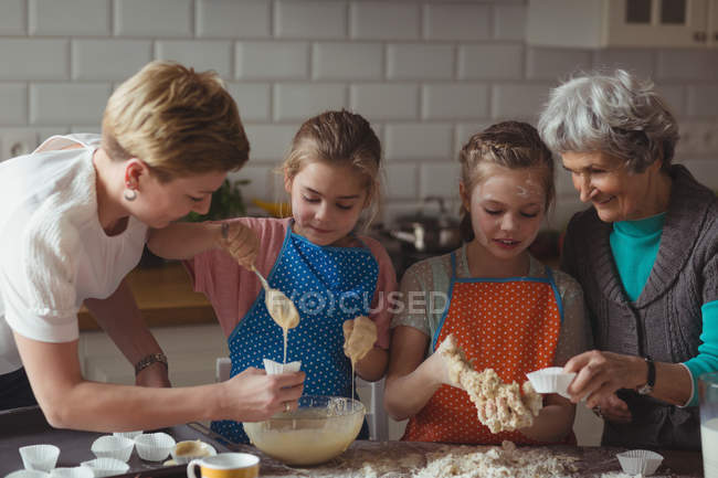 Семья из нескольких поколений готовит кекс на кухне дома — стоковое фото