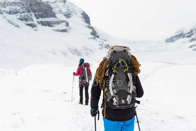 Visão traseira do casal andando em uma montanha coberta de neve durante o inverno — Fotografia de Stock