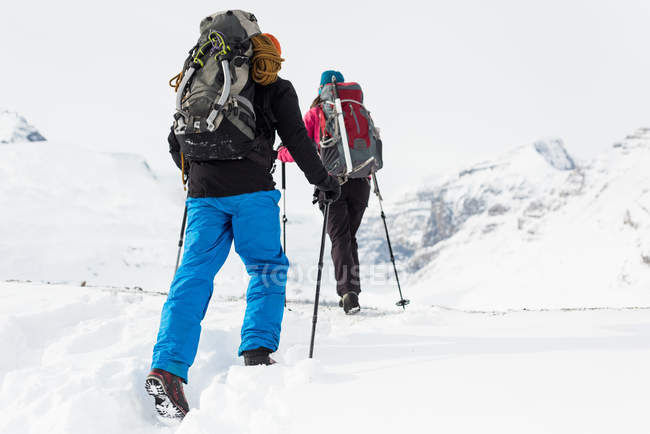 Visão traseira do casal andando em uma montanha coberta de neve durante o inverno — Fotografia de Stock