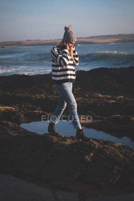 Jeune femme marchant sur le rocher à la plage — Photo de stock