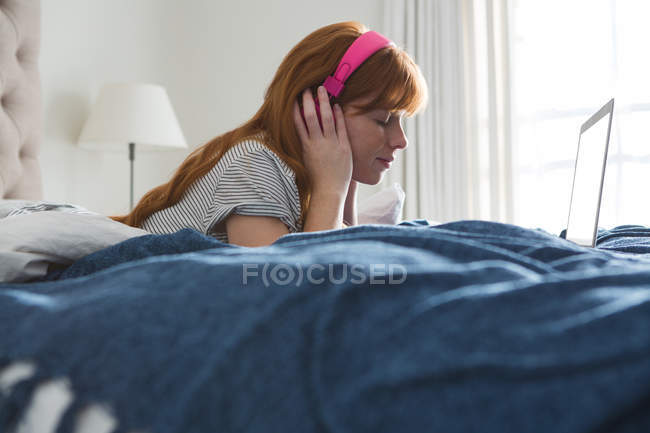 Donna con cuffie che ascolta musica in camera da letto a casa — Foto stock