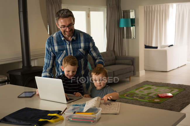 Papà e i suoi figli usano il portatile a casa — Foto stock