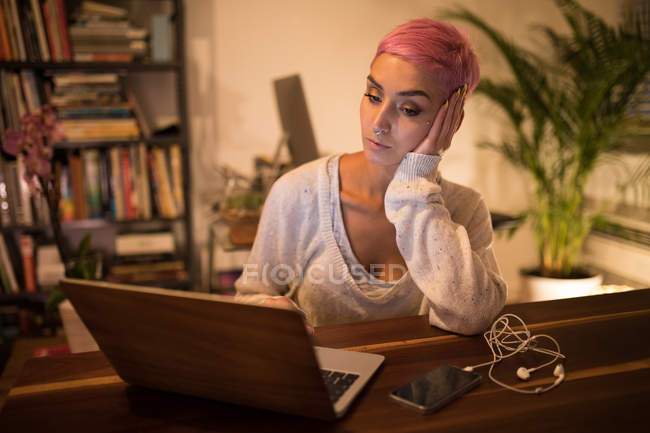 Mujer con estilo utilizando el ordenador portátil en casa - foto de stock