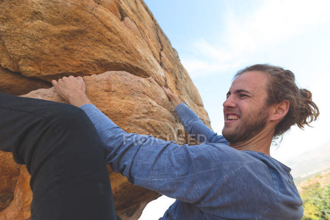 Мужчина-турист поднимается на скалистую гору в сельской местности в солнечный день — стоковое фото