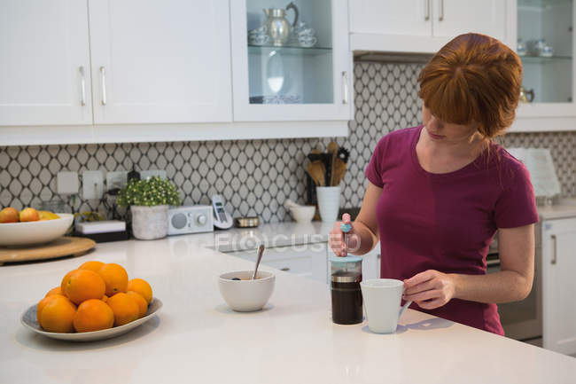 Donna che prepara caffè nero in cucina a casa — Foto stock