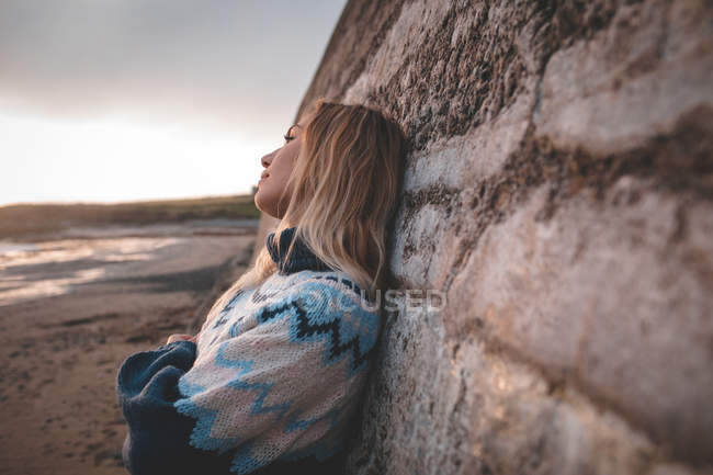 Mulher pensativo encostado contra a parede em uma praia — Fotografia de Stock