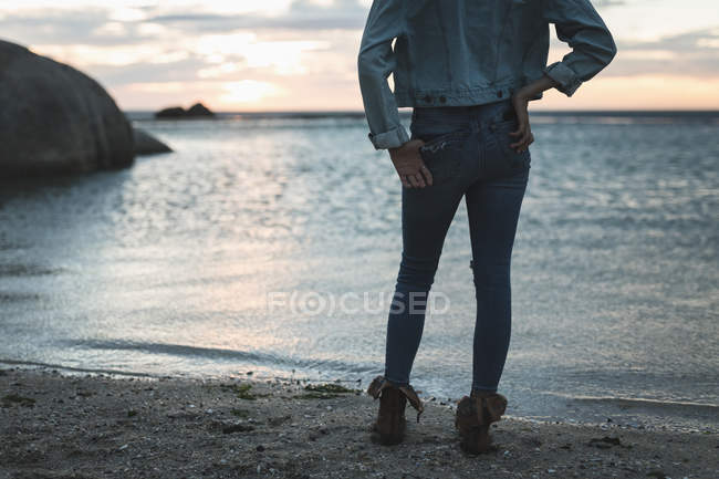 Вид ззаду жінки, дивлячись на пляж в сутінках — стокове фото