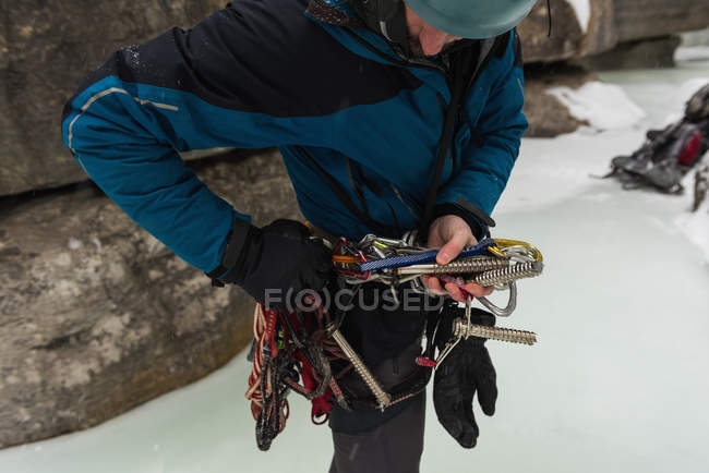 Male rock climber wearing harness near rocky mountain during winter — Stock Photo
