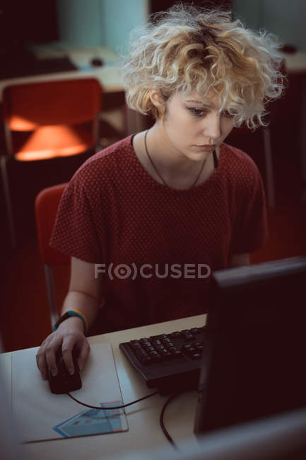 Mujer joven trabajando en la computadora en la biblioteca - foto de stock