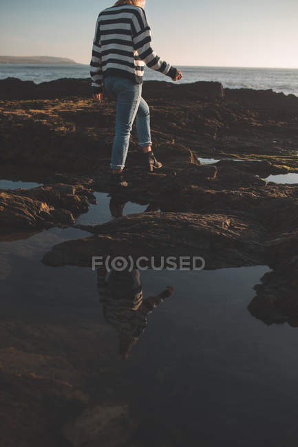 Frau läuft an einem sonnigen Tag über Felsen am Strand — Stockfoto