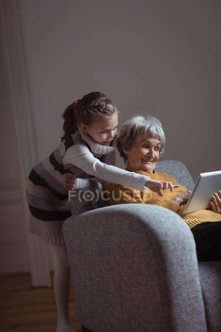 Бабуся і онука використовують цифровий планшет у вітальні вдома — стокове фото
