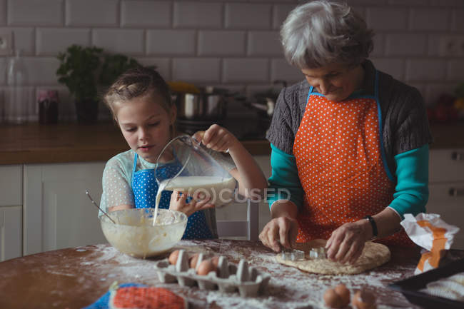 Бабушка и внучка готовят дома печенье на кухне. — стоковое фото